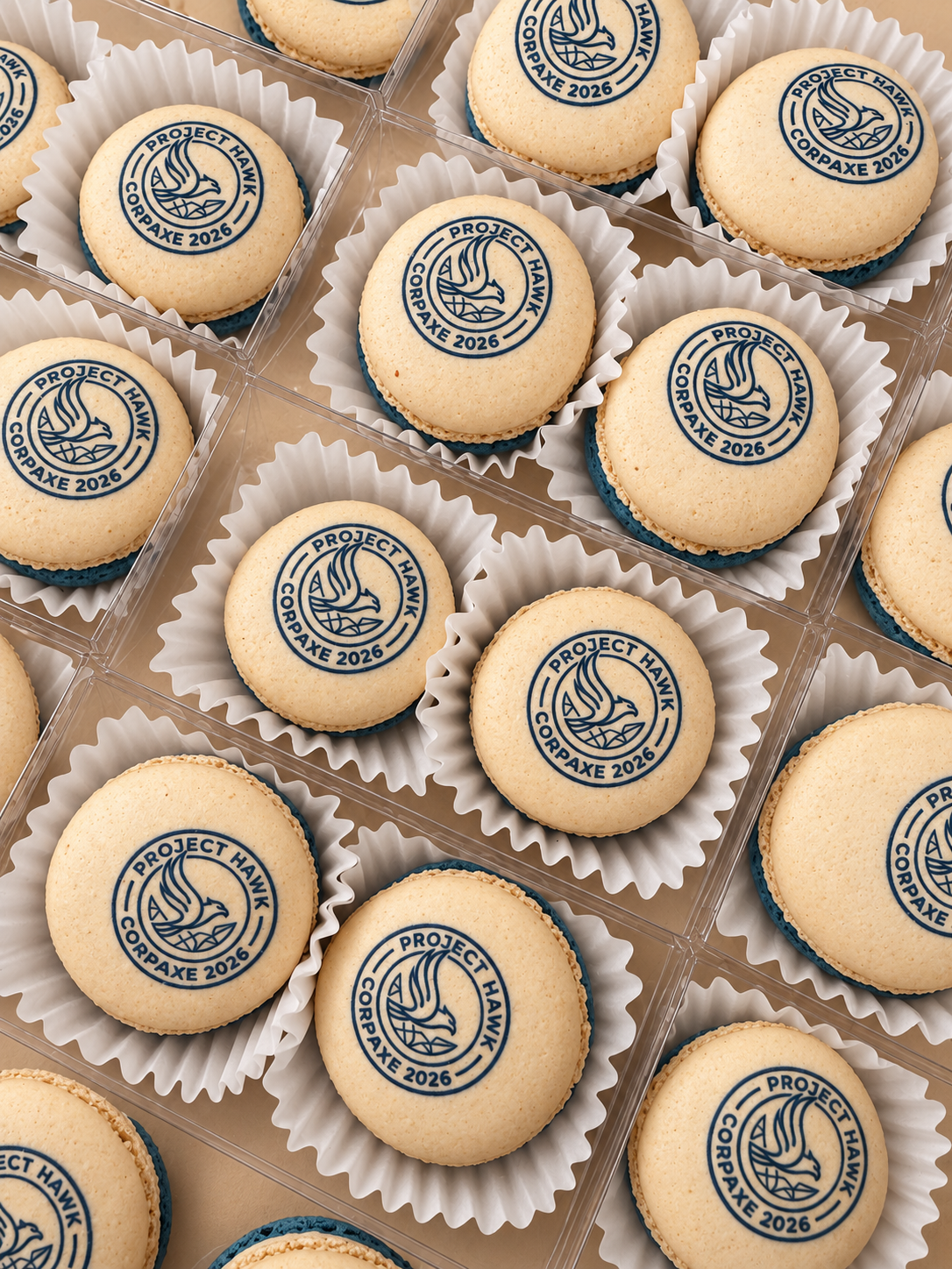 Ivory macarons printed with a navy circular emblem in clear favor boxes