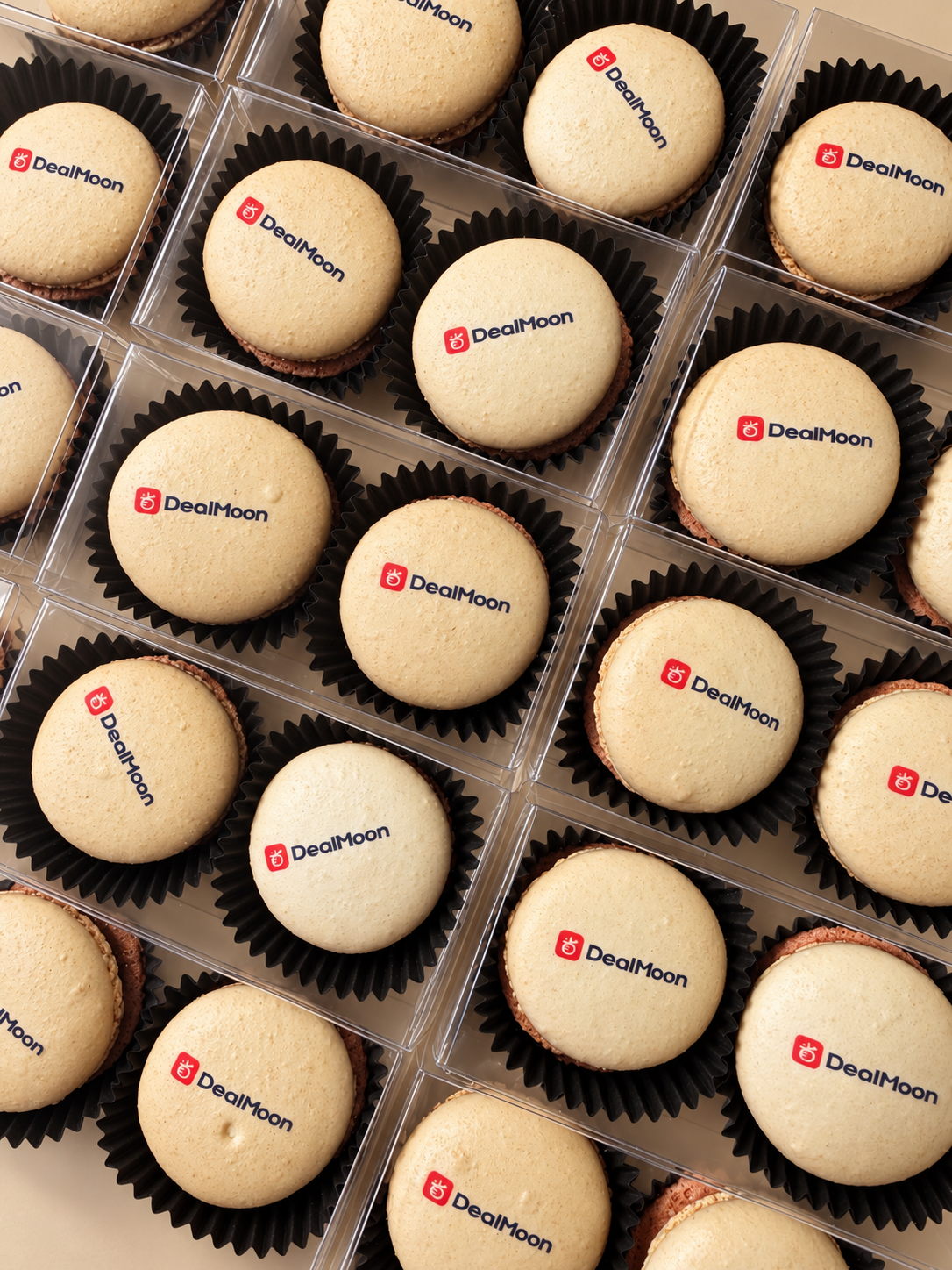 Ivory macarons printed with the red Dealmoon logo in black cups and clear boxes