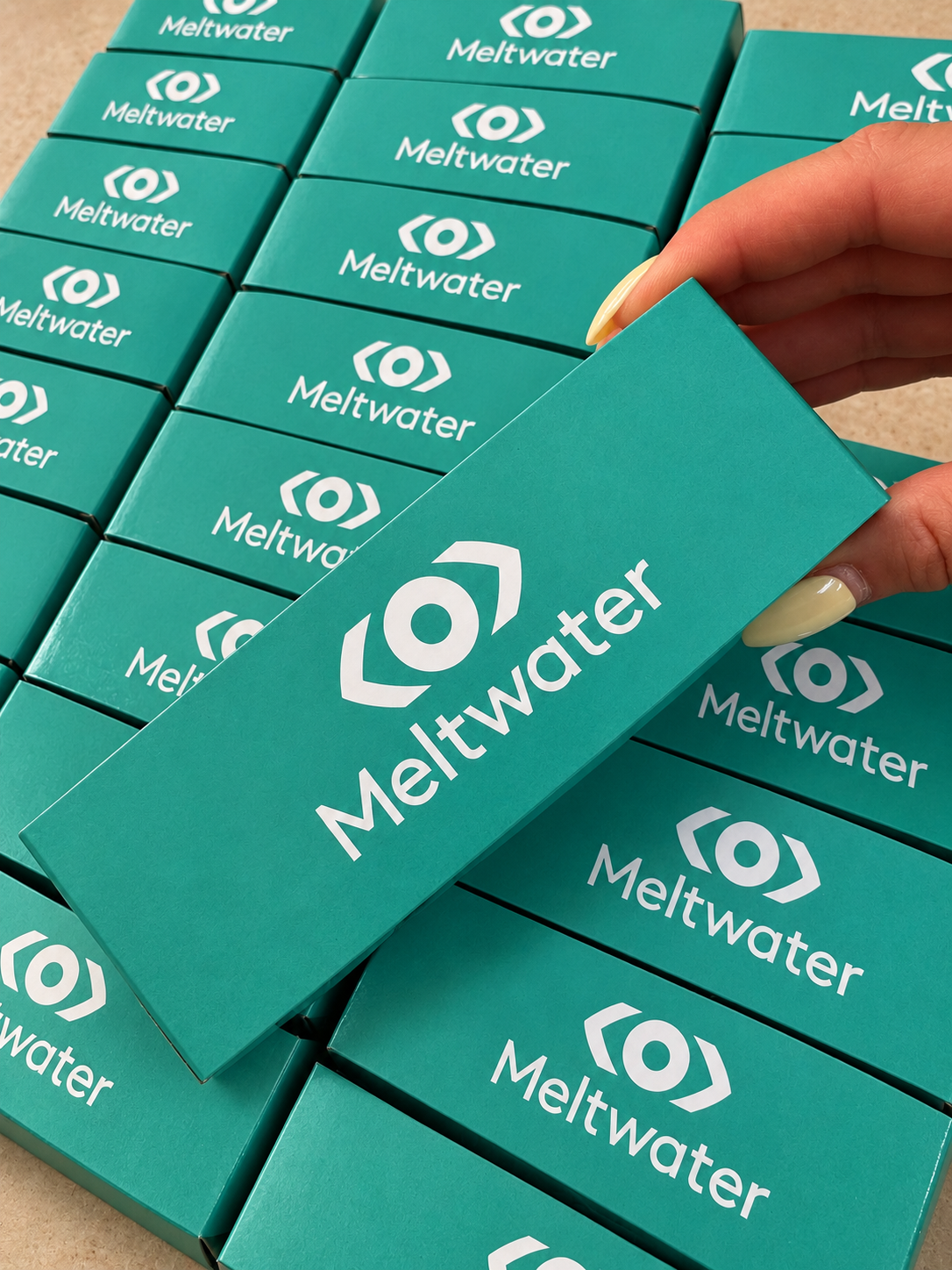 Macaron boxes wrapped in teal Meltwater branded sleeves