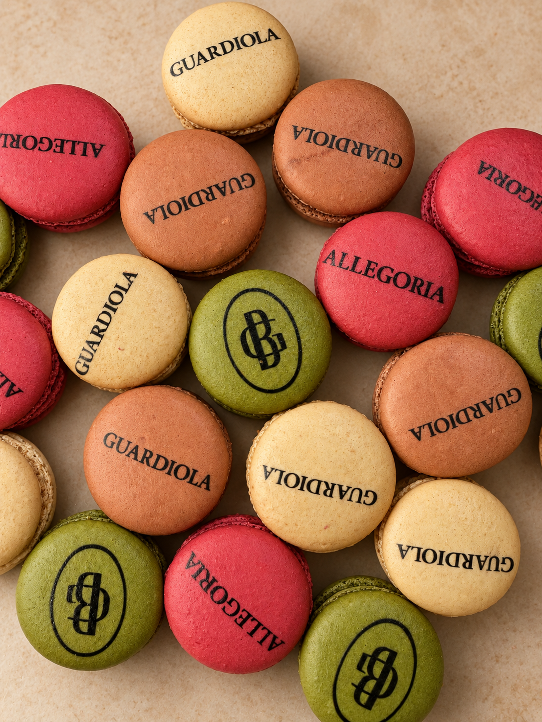 Green and pink French macarons printed with the Guardiola and Allegoria logos