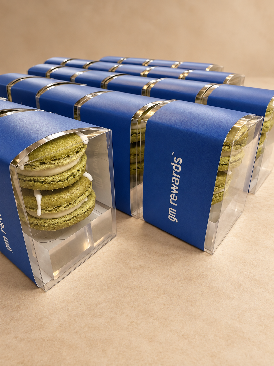 Blue gm rewards gift boxes with a clear window showing green macarons