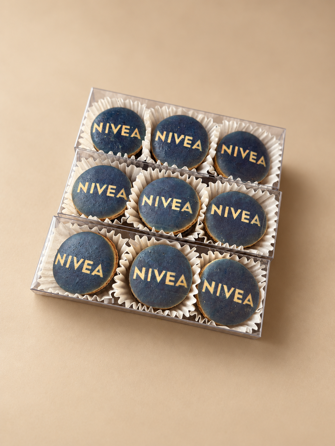 Clear gift box of navy macarons printed with the white NIVEA logo