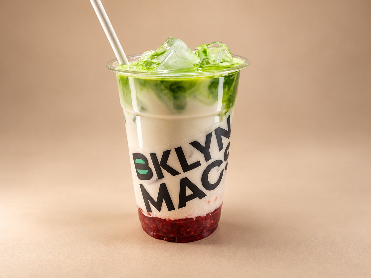 Iced matcha drink layered over a red fruit base in a BKLYN MACS cup