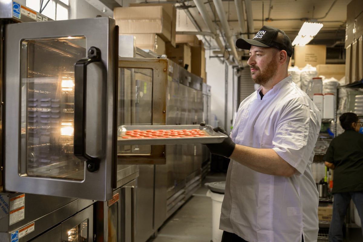 Gene sliding a tray of piped macaron shells into a convection oven