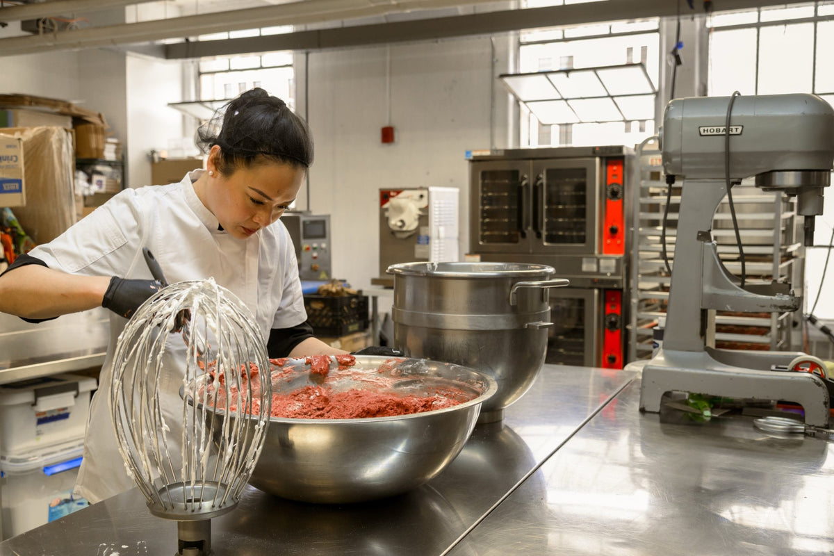 Rebecca folding pink macaron batter by hand in a large mixing bowl